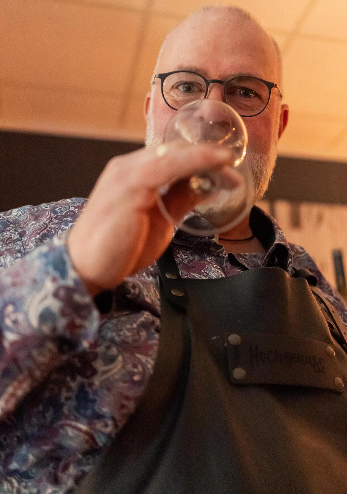 Der Ladenbesitzer trinkt aus einem Glas Wein.